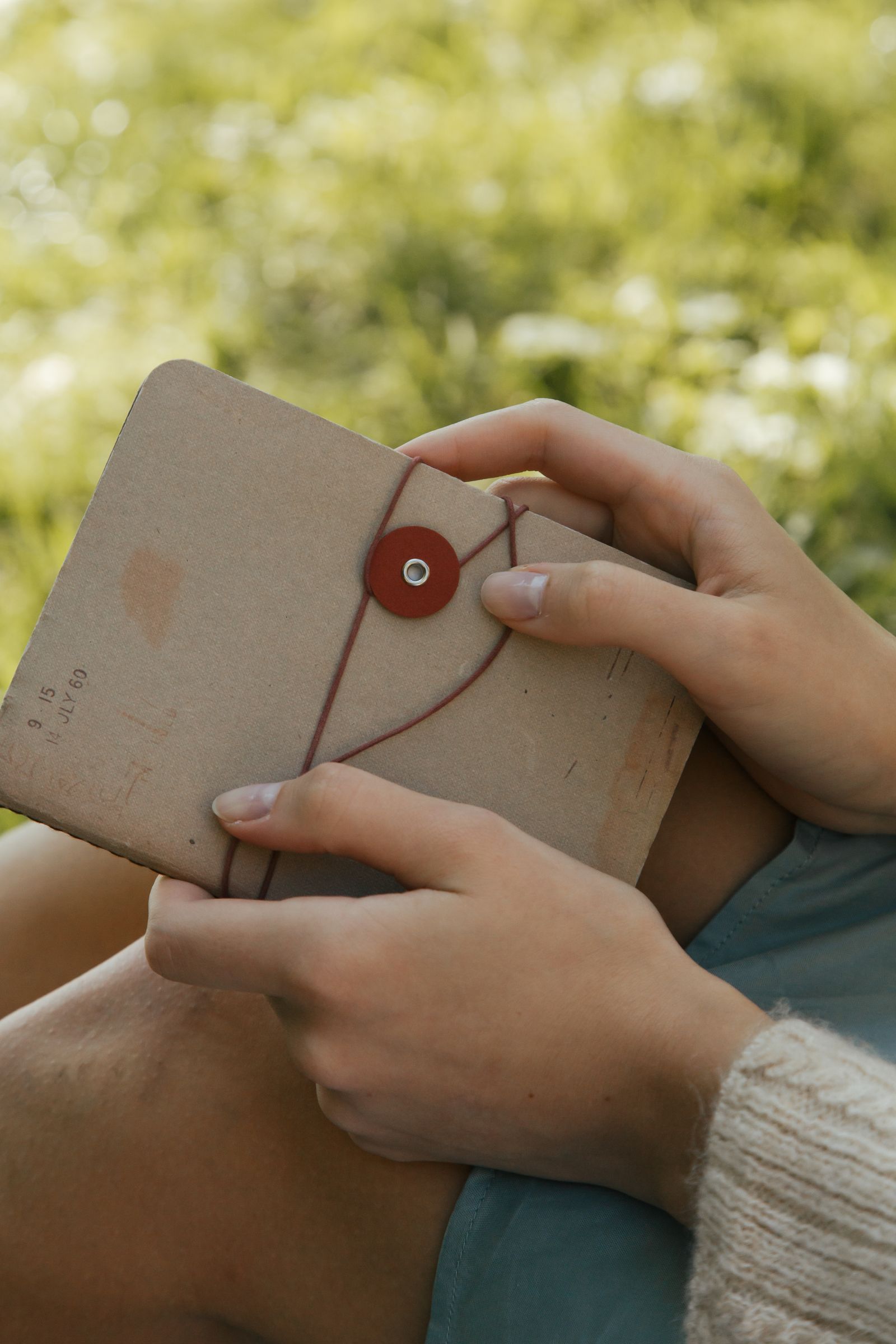 Hands holding a closed notebook outdoors