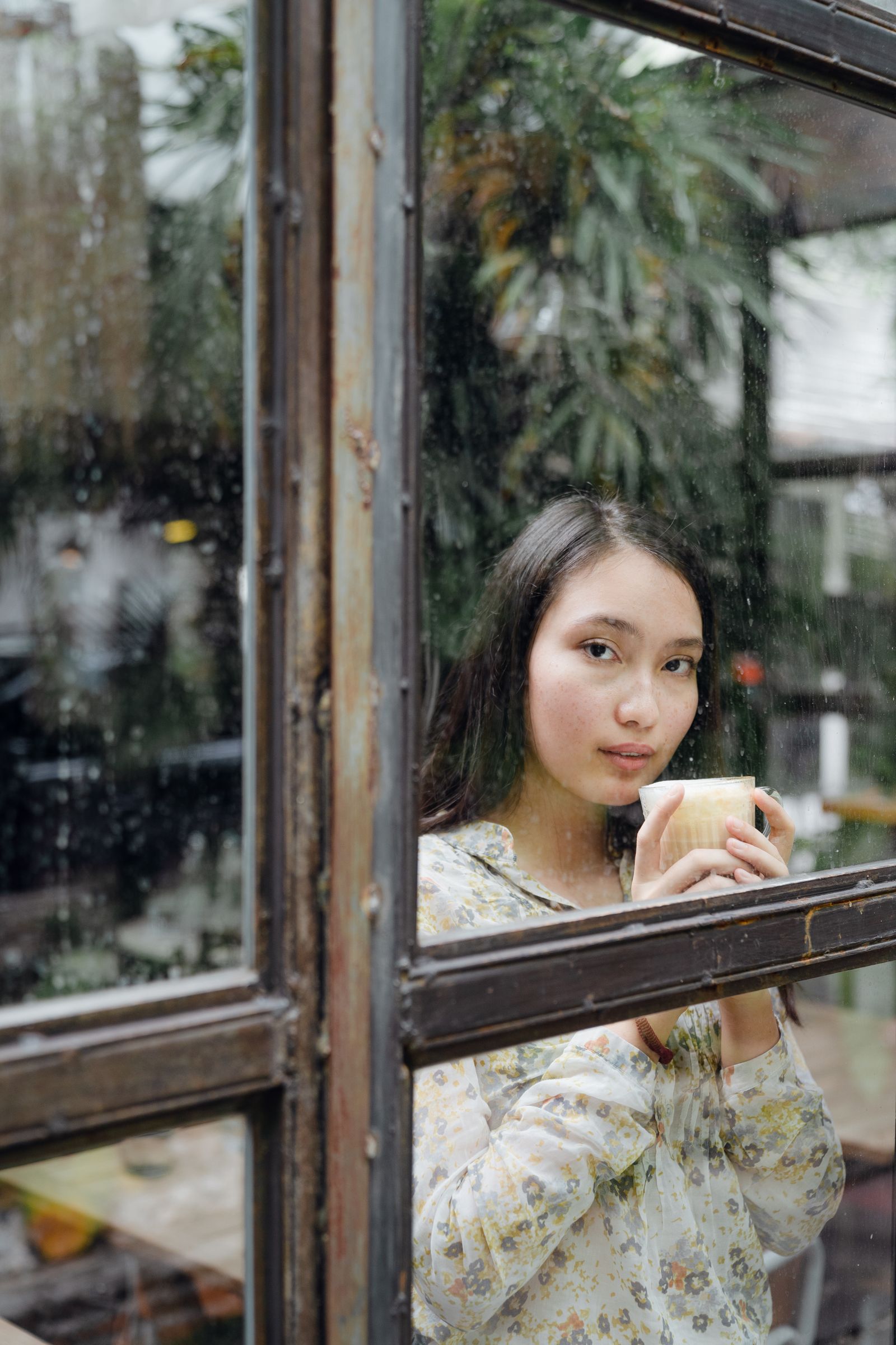 A woman holding a coffee by a café window